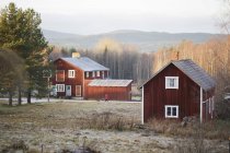 Rote Holzhäuser in herbstlicher Landschaft — Stockfoto