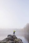 Young man fishing in lake on foggy day — Stock Photo