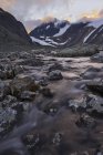 Scenic view of stream at foot of mountains at dusk — Stock Photo