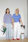 Young women standing by wall and holding drills — Stock Photo