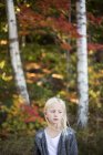 Portrait of blonde girl with autumn trees in background — Stock Photo