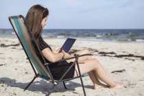 Teenager-Mädchen nutzt digitales Tablet am Strand — Stockfoto