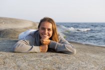 Girl resting on rock formation at seaside — Stock Photo