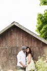 Man kissing woman in front of wooden barn, focus on foreground — Stock Photo