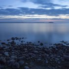 Meereslandschaft mit Leuchtturm in der Abenddämmerung und felsigem Ufer — Stockfoto