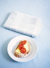 Тарелка с бутербродом и газета на голубой скатерти — стоковое фото