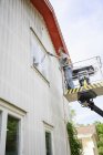 Man in cherry picker cleaning wall of house — Stock Photo