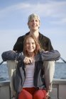 Portrait of teenage girl and young man sitting on boat — Stock Photo