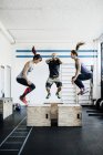 Les jeunes femmes et l'homme sautant dans la salle de gym — Photo de stock
