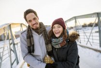 Молода пара на пішохідному мосту взимку, фокус на передньому плані — стокове фото