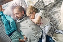 Pai dormindo com filhas na cama — Fotografia de Stock