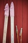 Old skis and ski poles leaning against red wall — Stock Photo