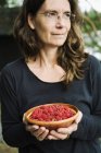 Mature woman holding bowl of raspberries — Stock Photo