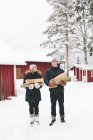 Молодая пара стоит и держит дрова с домами на заднем плане — стоковое фото
