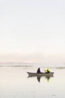 Молодые люди рыбачат в озере на закате — стоковое фото