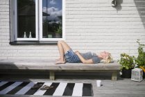 Side view of mature woman lying on bench — Stock Photo