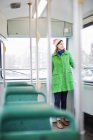 Молода жінка в зеленому пальто стоїть в трамваї — стокове фото
