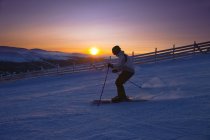 Вид збоку людини катається на лижах на заході сонця — стокове фото