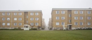 Edifícios residenciais e gramado verde no nevoeiro — Fotografia de Stock