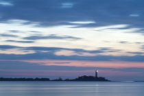 Sea landscape with lighthouse illuminated at dusk — Stock Photo