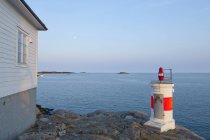 Маленький маяк на берегу моря с закатом неба — стоковое фото