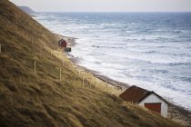 Cabanas ao longo da costa por mar com ondas de surf — Fotografia de Stock