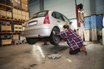 Female mechanic wearing checkered shirt adjusting wheel — Stock Photo