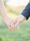 Cropped view of holding hands of newlyweds, selective focus — Stock Photo