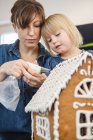 Mother and daughter making gingerbread house, differential focus — Stock Photo