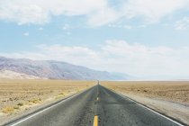 Empty road and mountains in bright sunlight — Stock Photo