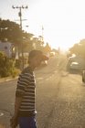 Junge steht auf Stadtstraße in pazifischem Hain — Stockfoto