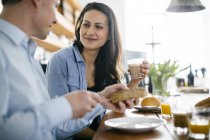 Couple eating breakfast at table, focus on background — Stock Photo