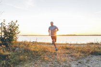 Mittlerer erwachsener Mann joggt am Strand — Stockfoto