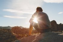 Uomo seduto sulla roccia nel Parco Nazionale di Joshua Tree e guardando il tramonto — Foto stock