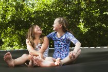 Two girls sitting on trampoline on sunny day — Stock Photo