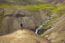 Turista olhando para córrego e cachoeiras no vale rochoso na Islândia — Fotografia de Stock