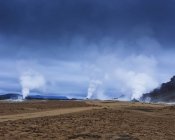 Dampf über heißen Quellen mit Gebirgskette in Island — Stockfoto