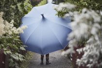 Woman with umbrella walking in garden — Stock Photo
