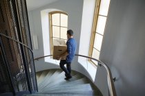 Vista ad alto angolo di uomo che cammina su gradini e scatola di trasporto — Foto stock