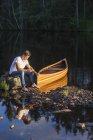 Чоловік сидить на валуні посеред озера — стокове фото