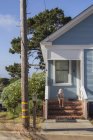 Ragazza seduta sui gradini di fronte alla casa blu a Pacific Grove — Foto stock