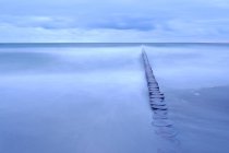 Paysage marin avec brise-lames sous un ciel humide — Photo de stock