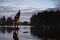 Homme debout sur la pierre dans le lac tenant canot — Photo de stock