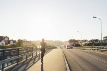 Vue arrière de la jeune femme jogging sur le pont — Photo de stock