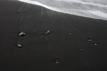 Sable noir et rochers à la surface de la plage, Islande — Photo de stock