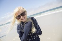 Sorridente ragazza bionda che indossa occhiali da sole sulla spiaggia — Foto stock