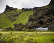 Хатини, побудований на схилі гори в пишною зелені долини, Ісландія — стокове фото