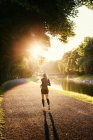 Jogger correre lungo il vicolo lungo il canale nel parco — Foto stock