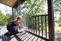 Mature woman painting porch railing — Stock Photo