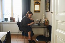 Mulher em vestido preto usando laptop na mesa — Fotografia de Stock